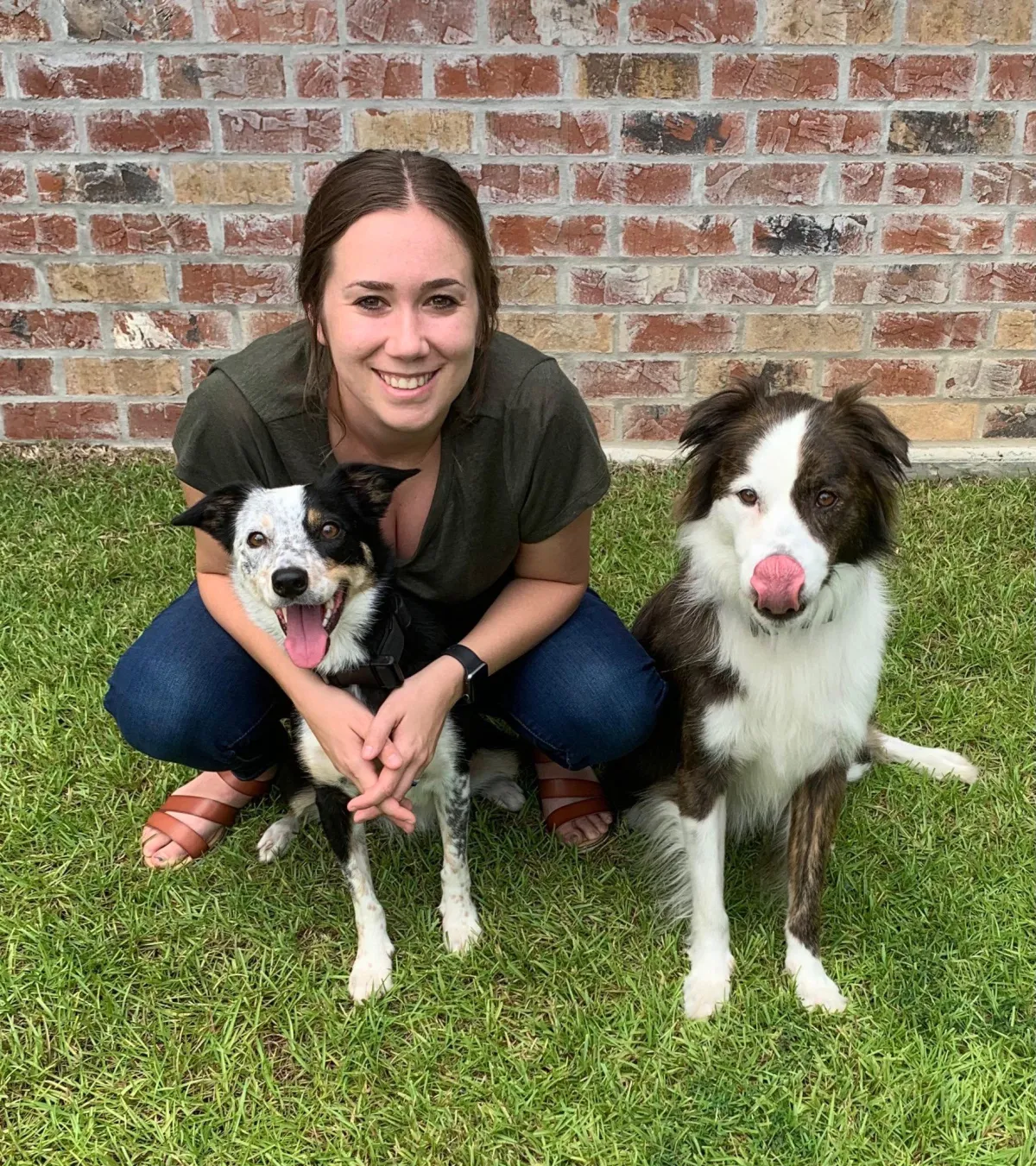 Company owner squatting down and two dogs sitting 