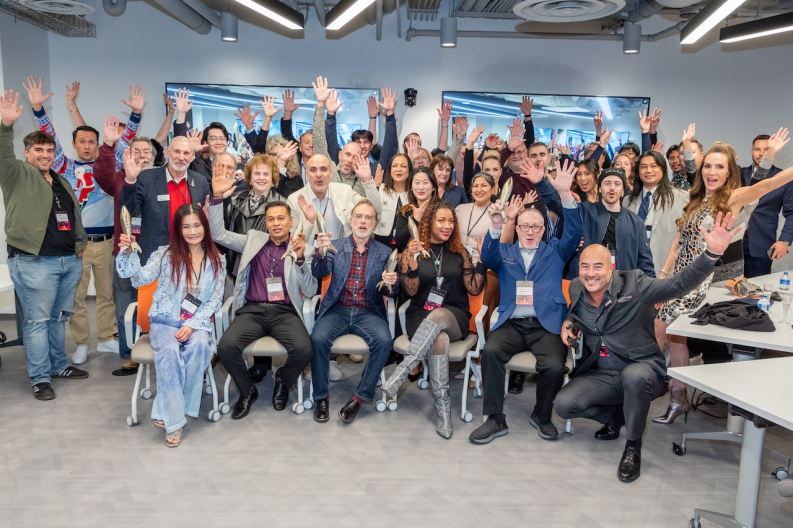 Large group of TCVN founders, members, and entrepreneurs celebrating with hands raised at a Tech Coast Venture Network event