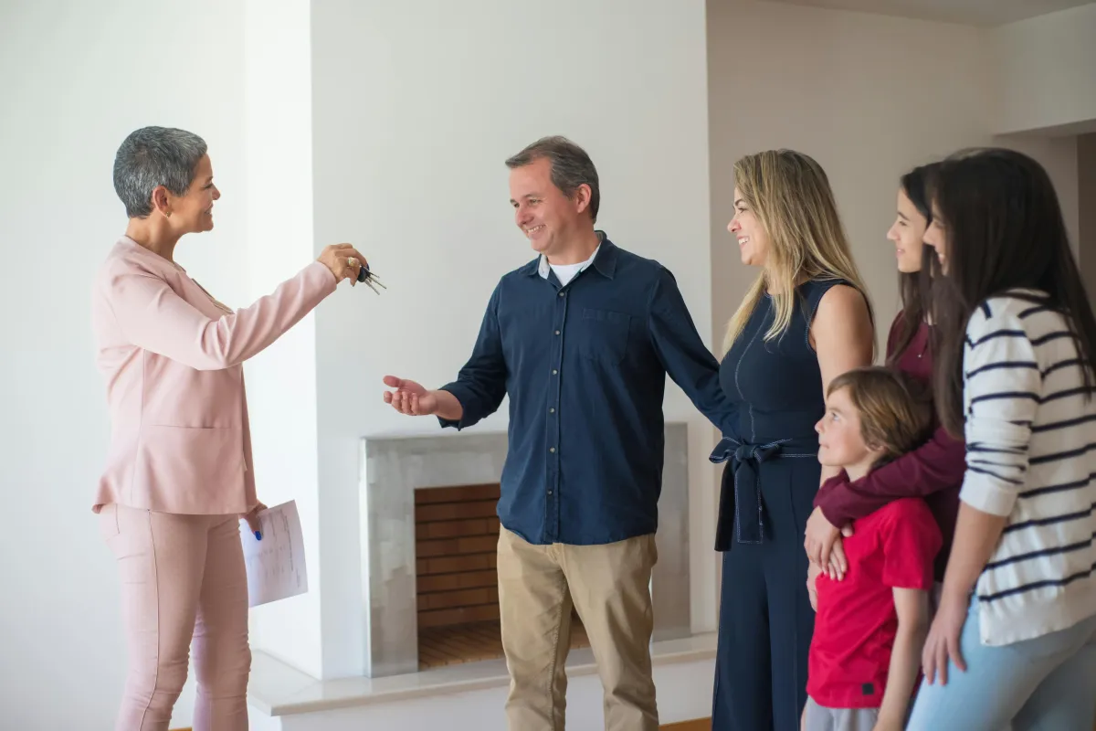 Real estate agent handing house keys to happy family in new home living room
