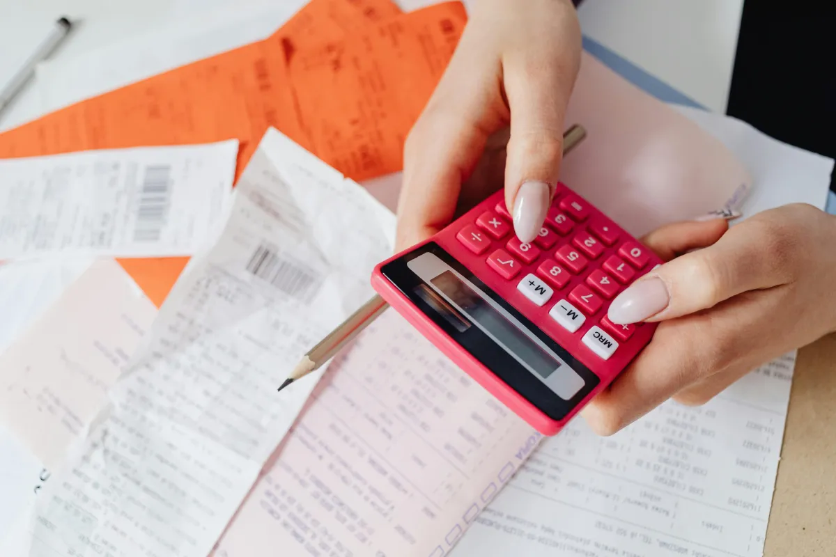 Free Hands using a red calculator surrounded by financial documents and receipts, symbolizing financial management. 