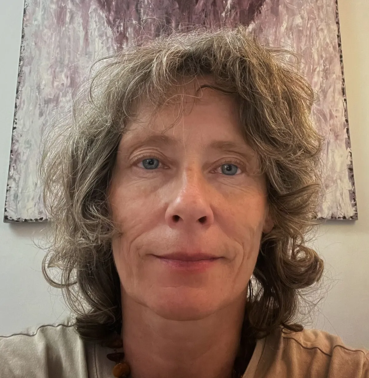 Portrait photo of a woman with short curly blonde hair.