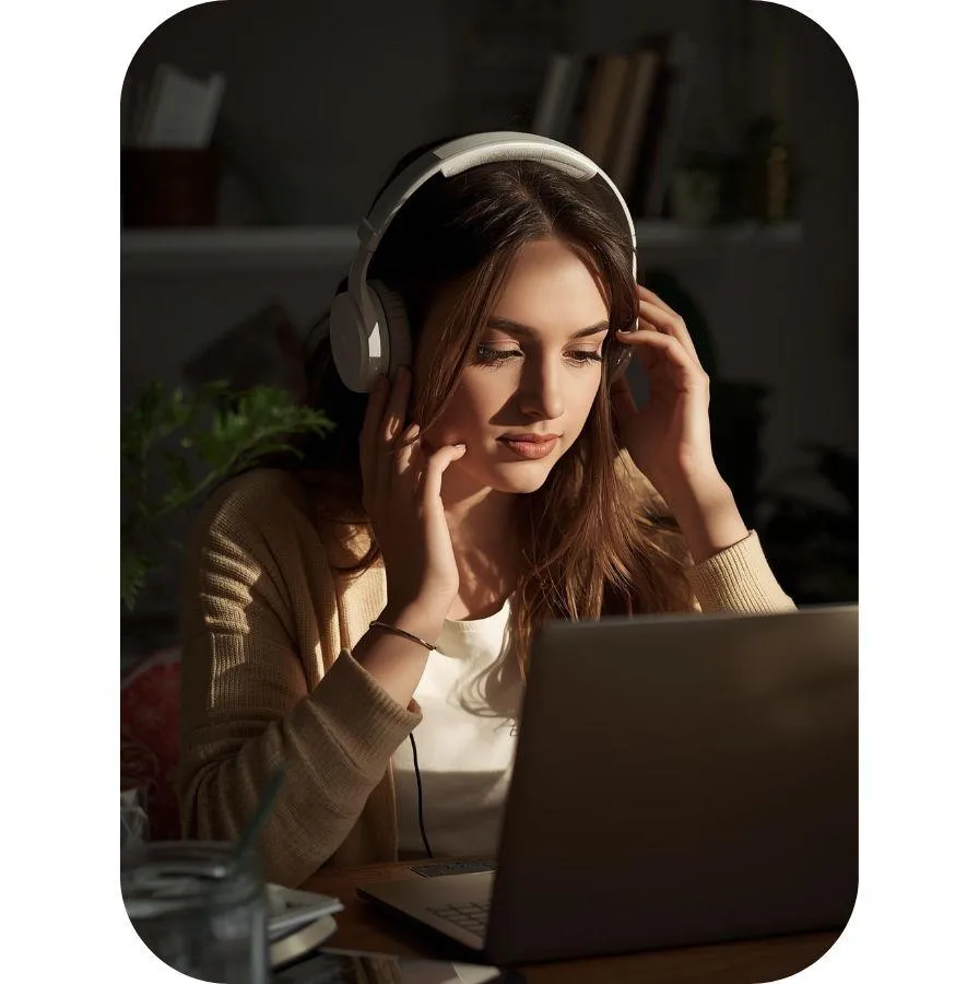 Woman sitting at her laptop with her headphones studying.