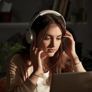 Woman sitting at her laptop with her headphones studying.