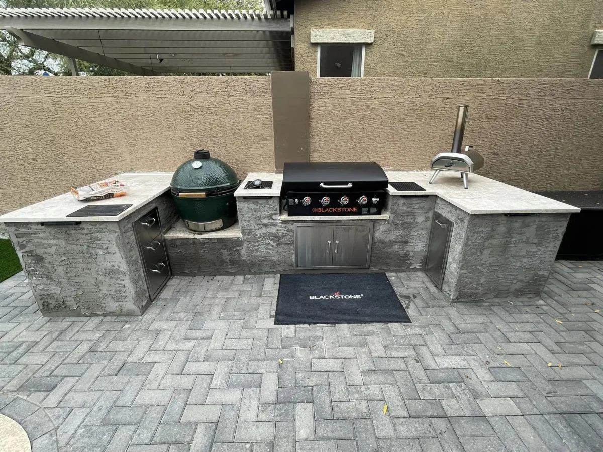 Custom-built outdoor kitchen with premium appliances, durable countertops, and a stylish paver patio for outdoor entertaining