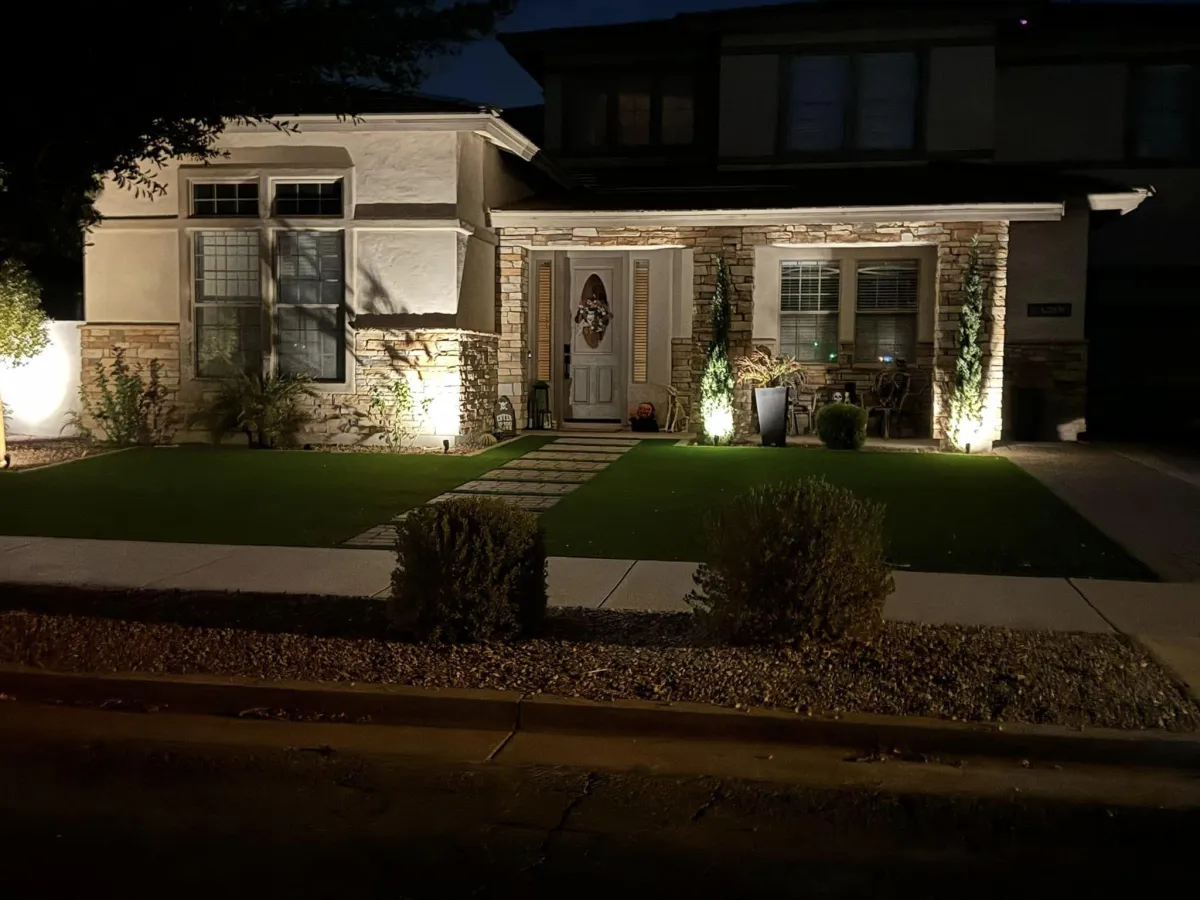 Front yard with energy-efficient outdoor lighting and professional landscaping, enhancing curb appeal and nighttime visibility.