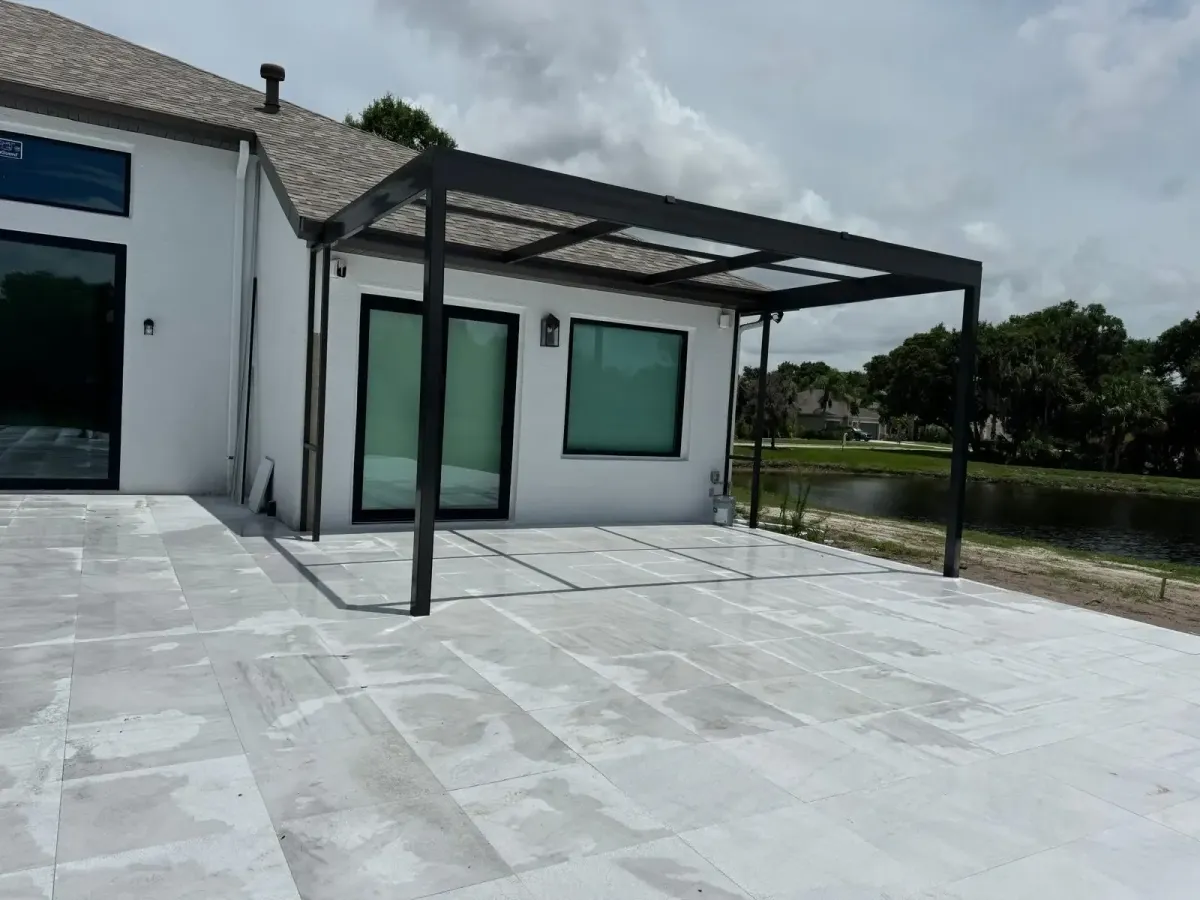 Metal pool enclosure structure installed on a home’s patio beside a lake