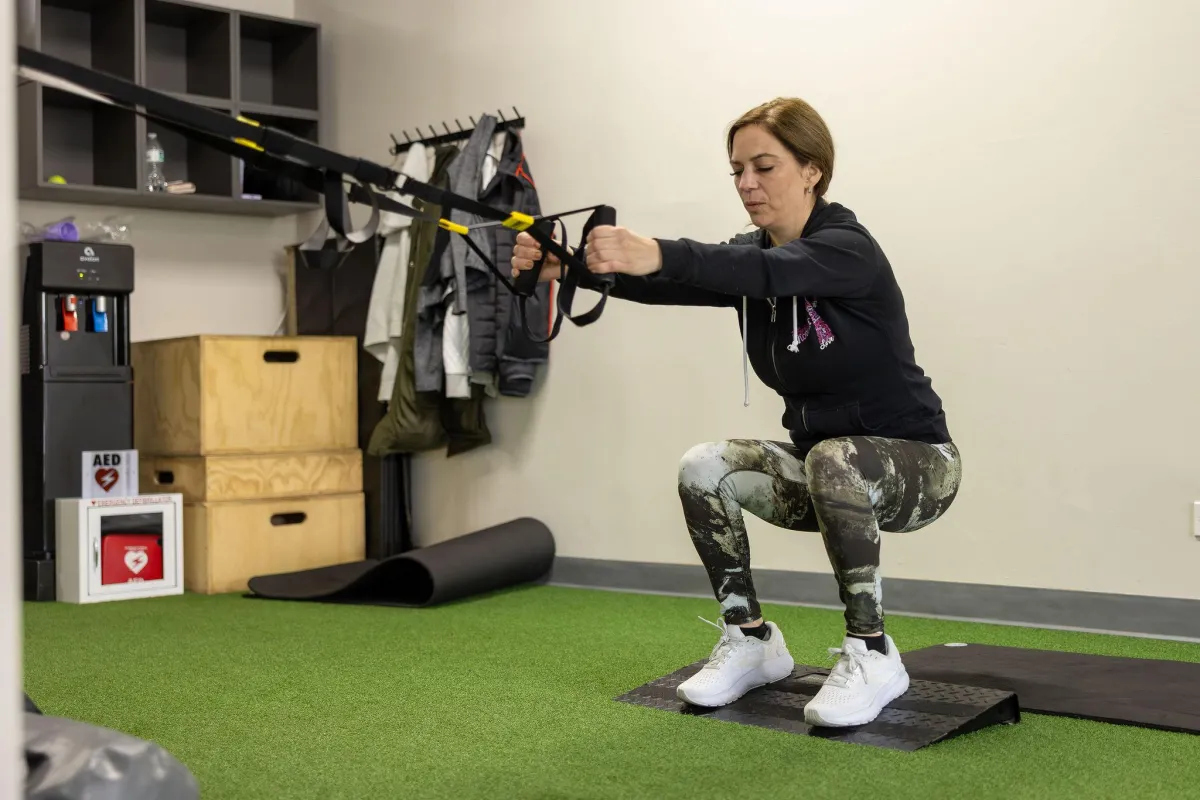 woman wearing black sports bra and white legging lifting dummbells