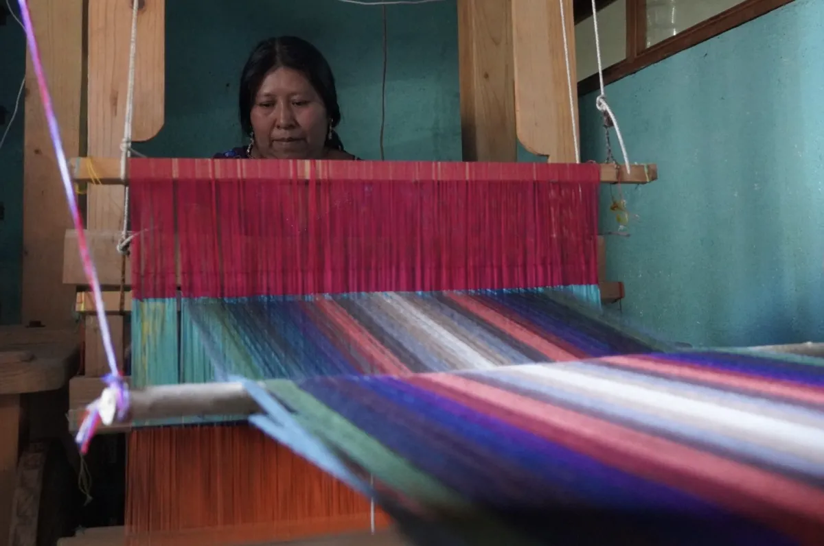 A woman is using a handloom to create a textile on part of a tour on ngos in Guatemala