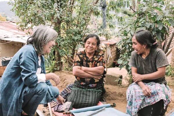 Women are talking over fabric, discussing natural indigo dye methods