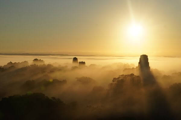 Watching the sunrise at Tikal above clouds and Mayan ruins in Petén Guatemala