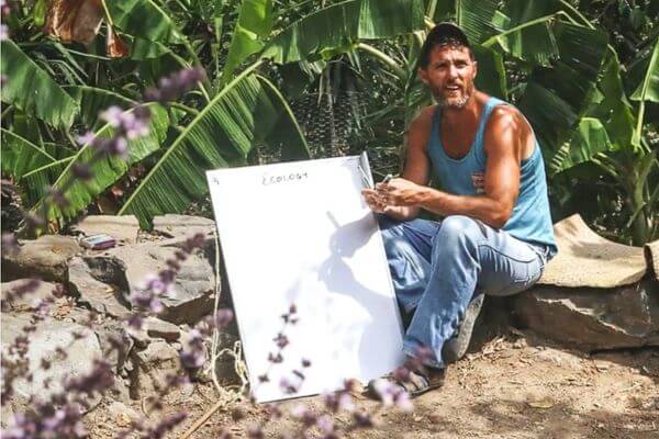 Neal Hegarty is holding a white board teaching students about Guatemala permaculture