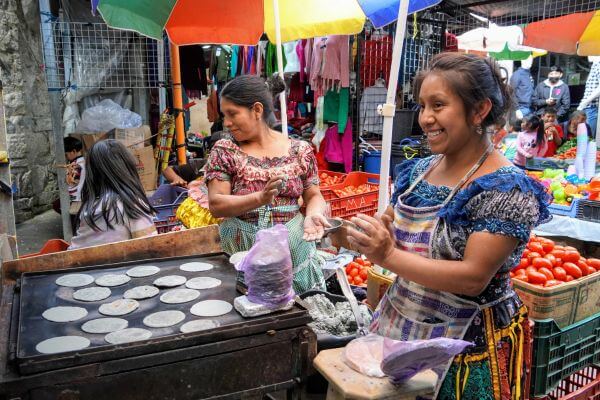 A woman is making tortillas in a market making Guatemalan street food