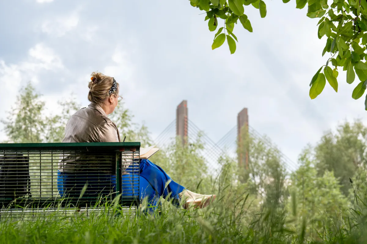 Anna sitting on a bench with her sketchbook overlooking the river the waal and the Martinus Nijhof bridge