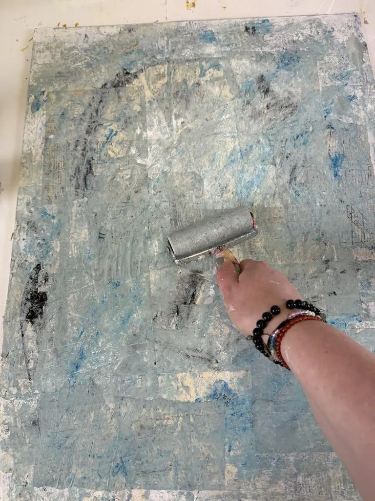hand with brayer on a light blue painting