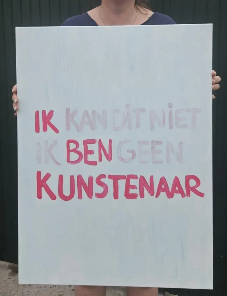Anna houdt een schilderij vast met de quote: Ik ben (geen) kunstenaar
