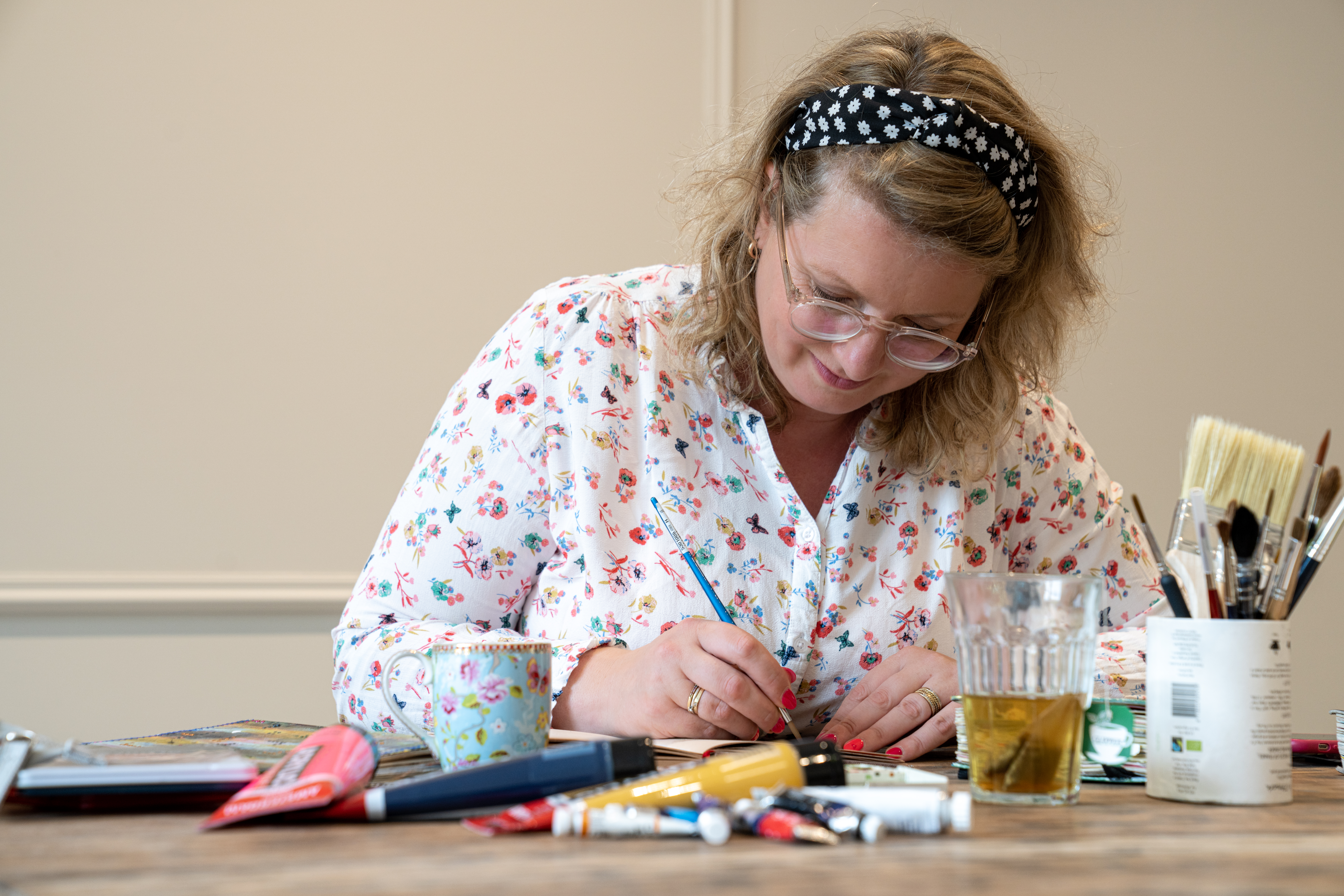 Anna working in a sketchbook on a table with art supplies