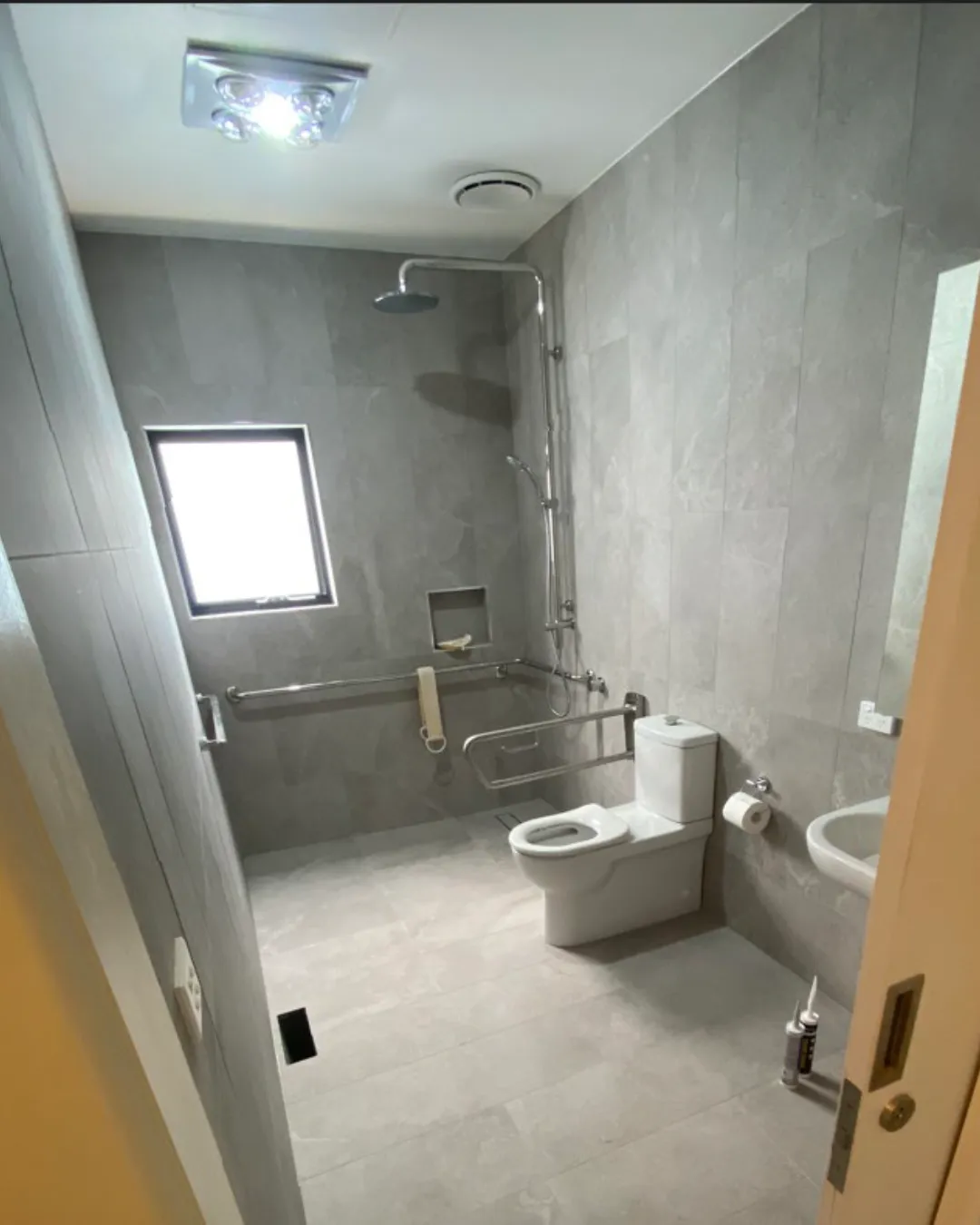 Generate an AI image of a bathroom vanity area with accessible clearances. Wide mirror, lever-style tapware, under-vanity clearance for mobility aid access. Warm white walls, timber accents. Feels like a high-end residential renovation.