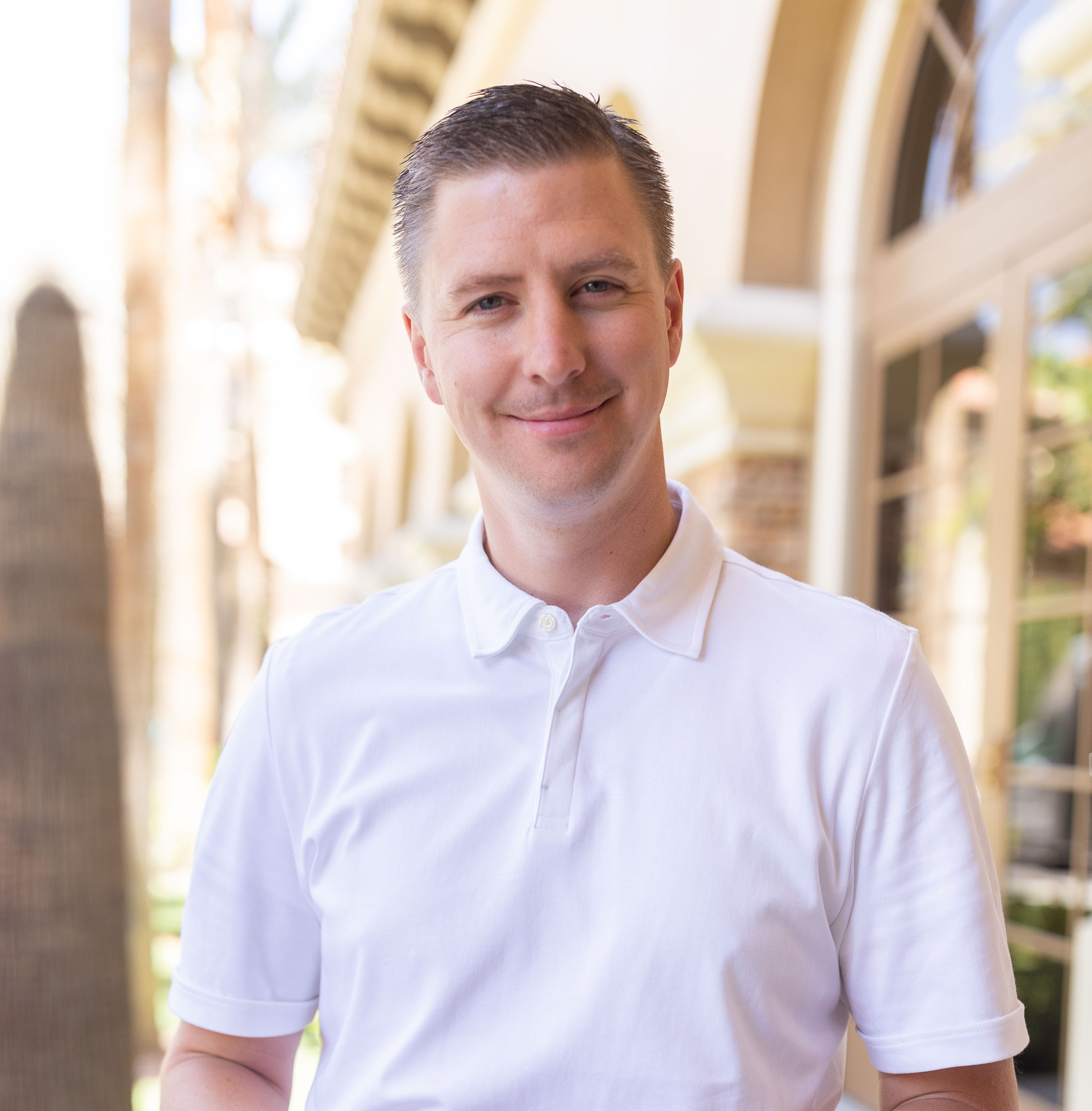 Mac Foulger, a middle-aged Caucasian man in a navy suit, smiling confidently in a professional office setting with certificates on the wall. The background is softly blurred, emphasizing his approachable demeanor and expertise.