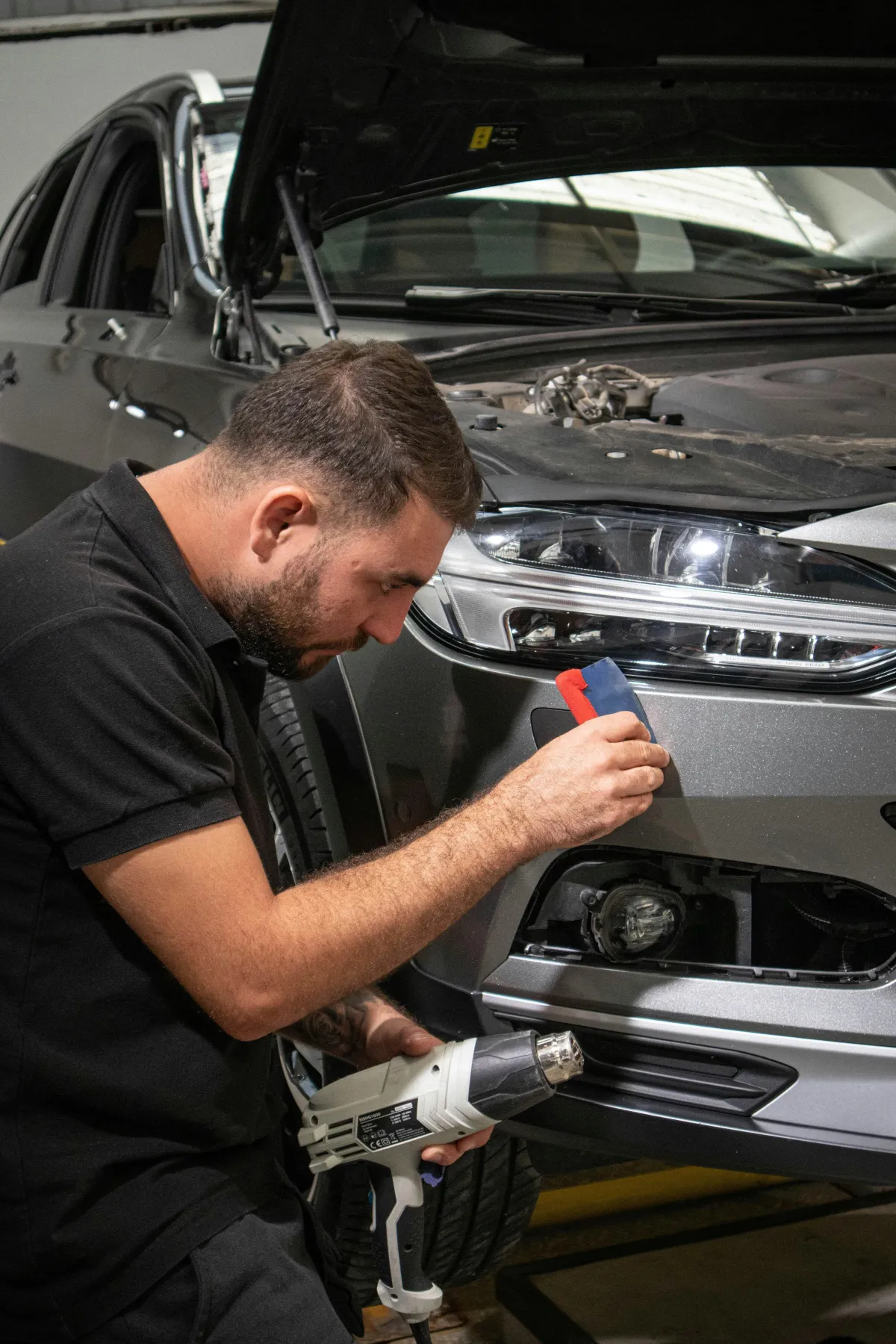 Detailer inspecting a vehicle's paint before PPF