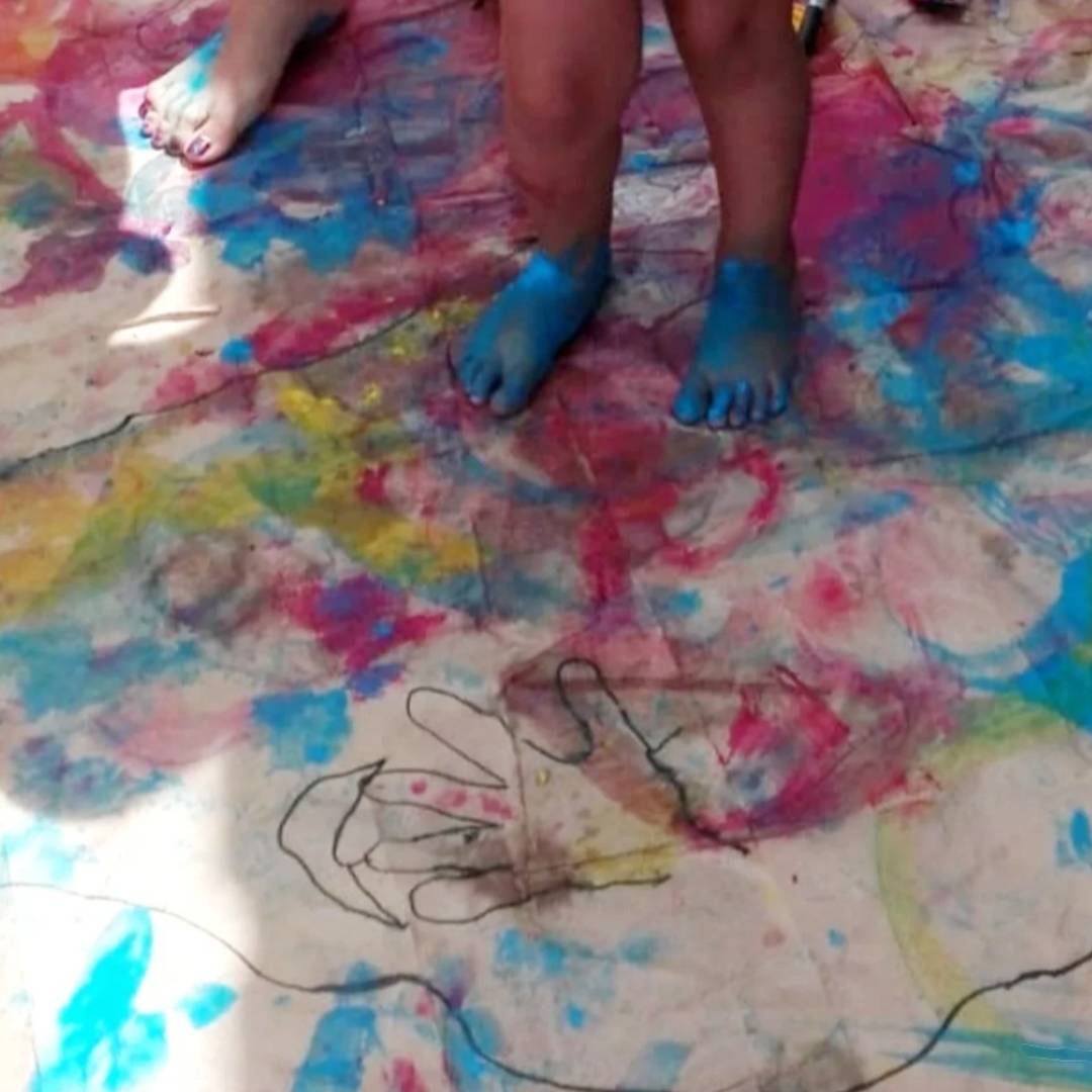 Musician playing acoustic guitar in a softly lit, intimate setting with art materials nearby