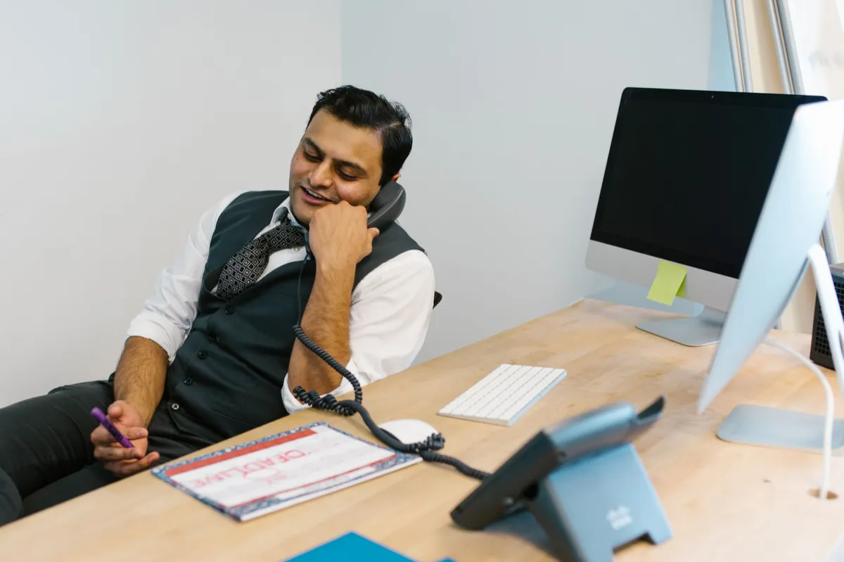 Smiling businessman engaged in a phone conversation at a modern office desk.