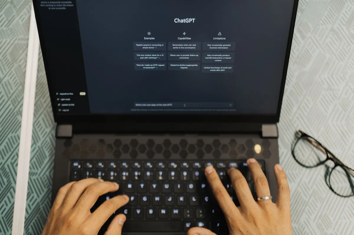 Hands typing on a laptop, automation and AI theme