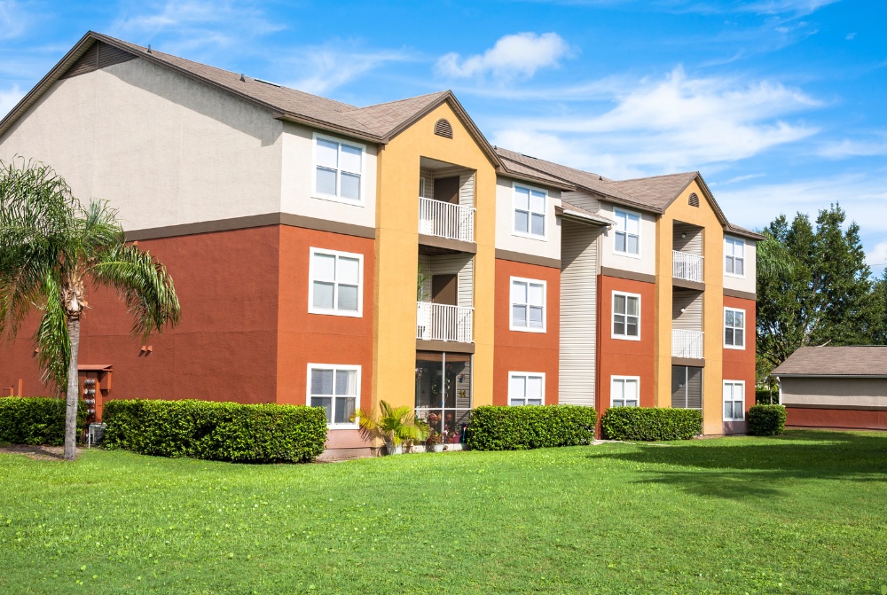 Modern Miami-style condo building with glass rail balconies and palm trees, ideal for condo inventory loan Miami and private condo inventory financing Miami.