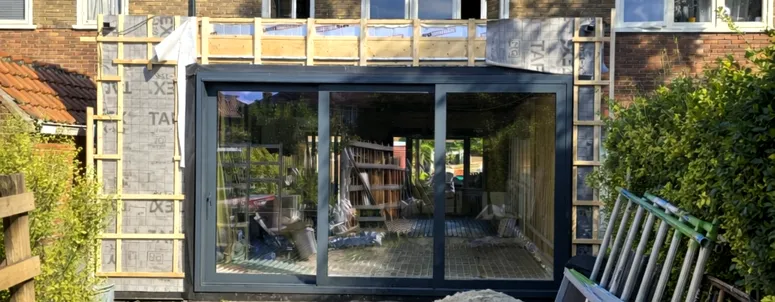 Sfeervol interieur tuinkantoor met open haard en glazen schuifwanden