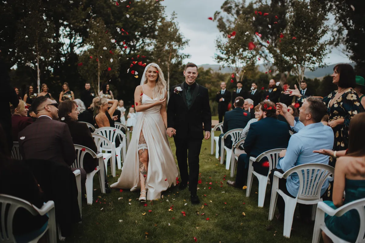 newlyweds exiting the ceremony under flower petals