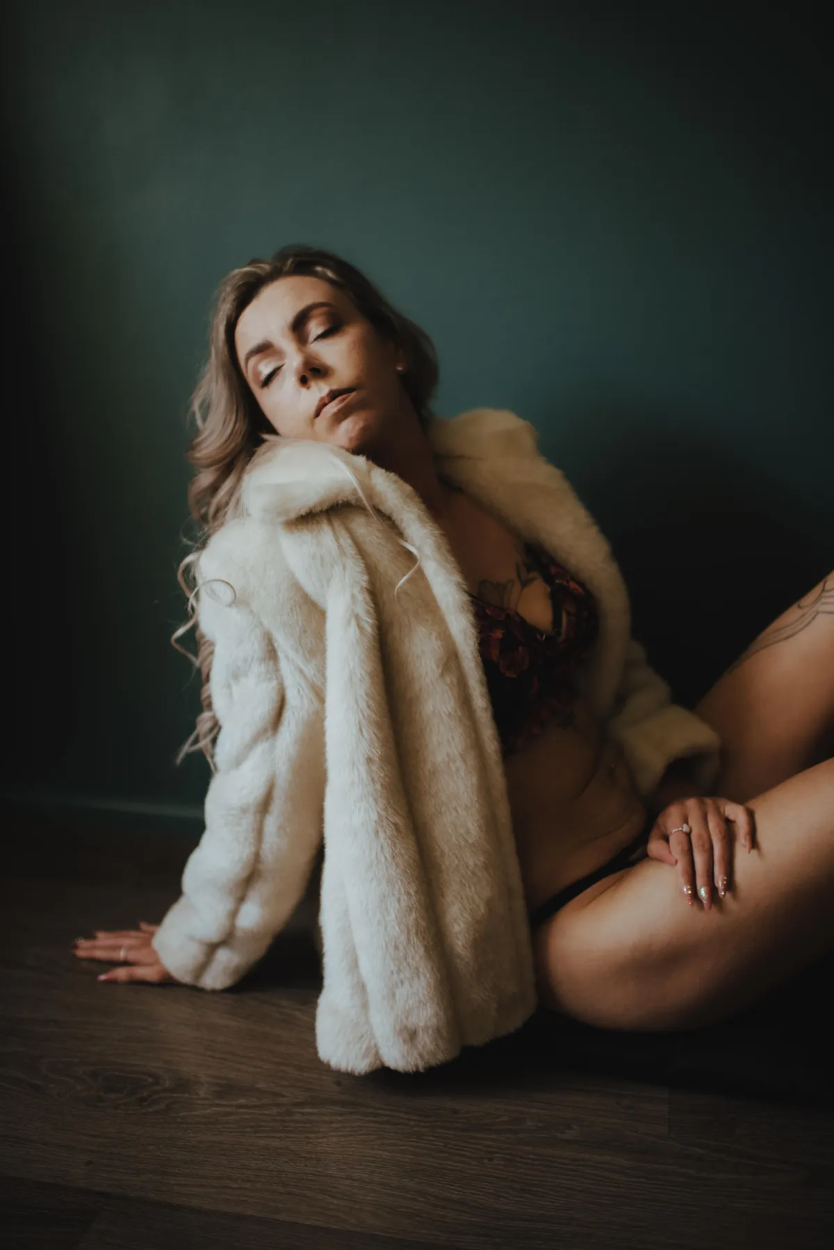 person leaning back against dark backdrop in faux fur coat