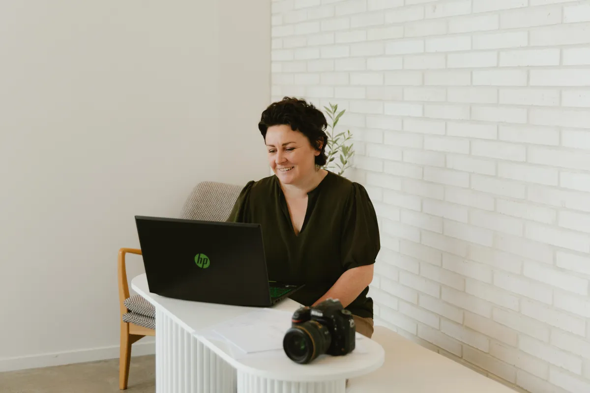 photographer sitting at bench with laptop and camera smiling