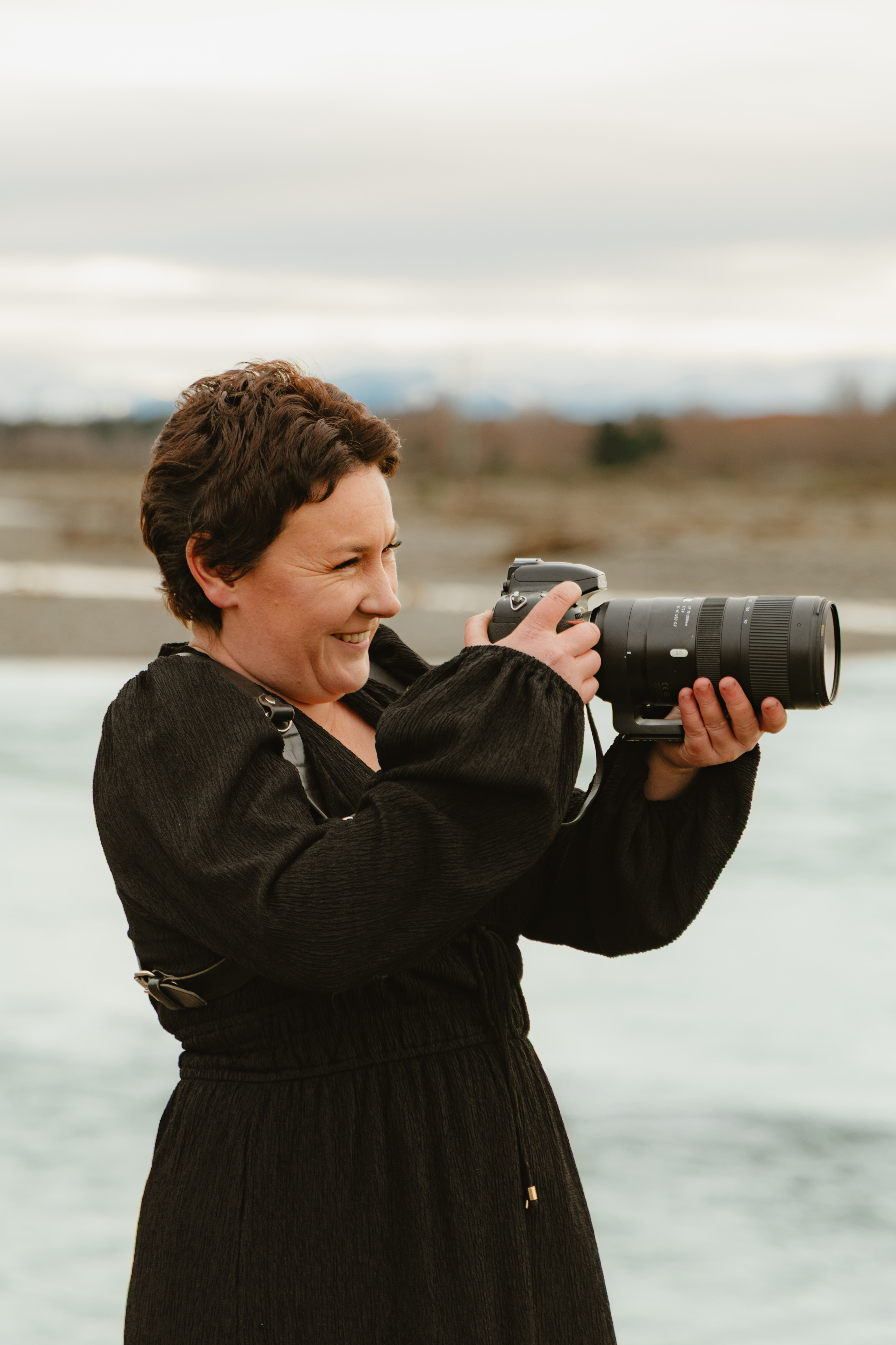 new zealand wedding and boudoir photographer smiling while photographing a couple