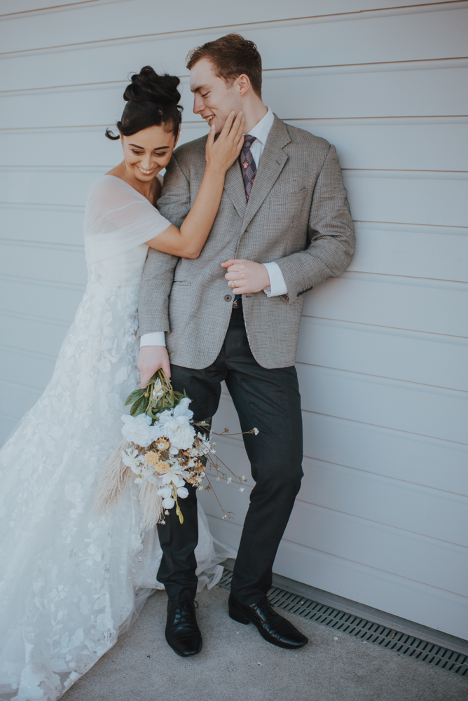 newlyweds laughing while leaning against a wall at Bramleys wedding venue