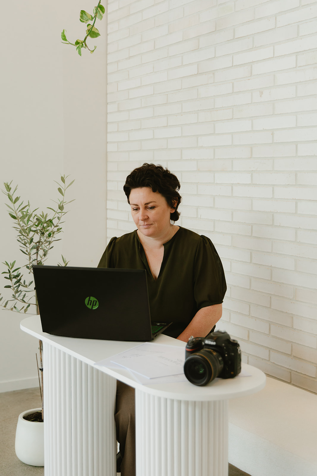 photographer sitting at bench with laptop and camera smiling
