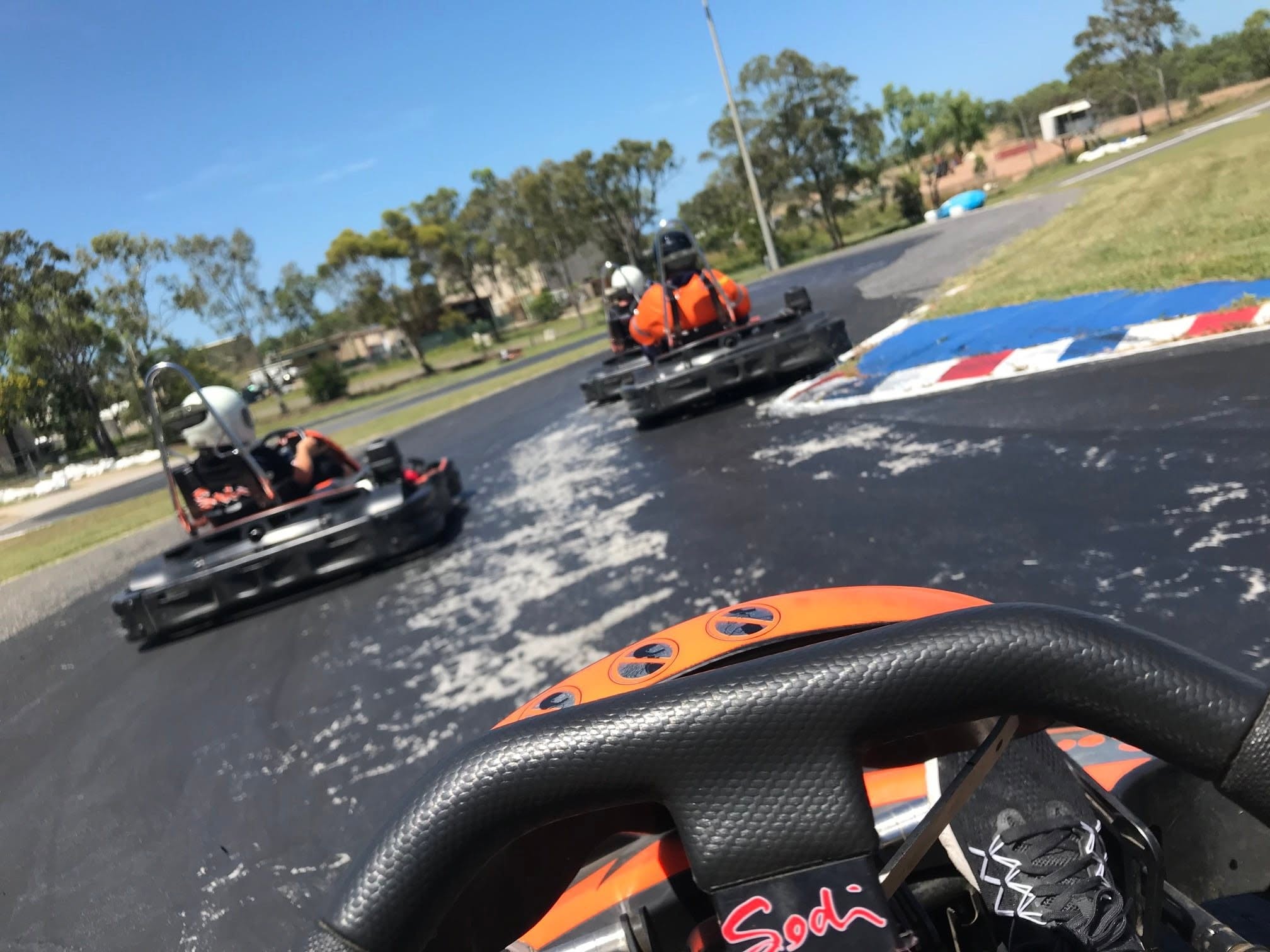 View from a FastKarts go-kart following other helmeted drivers around the track