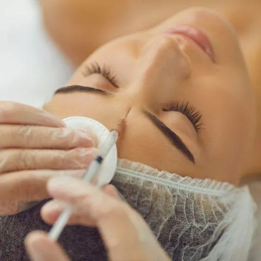 A person receiving Botox injections on their forehead by a professional in a clinical setting.