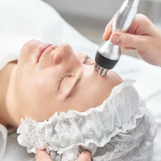 A person receiving a skin tightening treatment on their face with a handheld device by a professional in a clinical setting.
