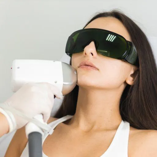 A person undergoing laser hair removal treatment on their face, wearing protective goggles, with a professional using a handheld laser device.