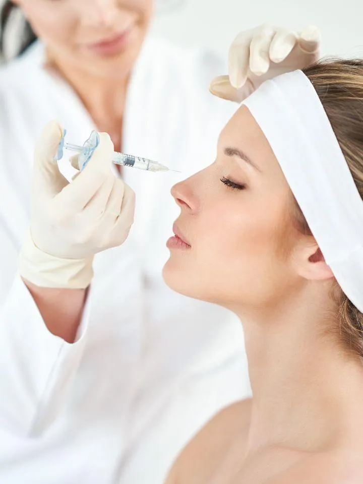 A medical professional injecting Botox into a woman's nose bridge area during a cosmetic treatment.