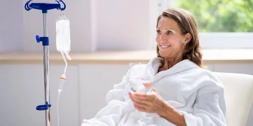 Smiling woman receiving IV drip in a wellness clinic setting, ideal for hydration, nutrient support, and energy restoration.
