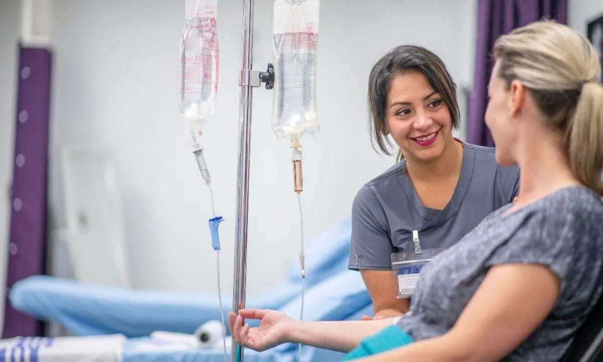 Nurse administering IV drip to smiling patient in a wellness clinic, symbolizing hydration, energy boost, and vitamin therapy benefits.