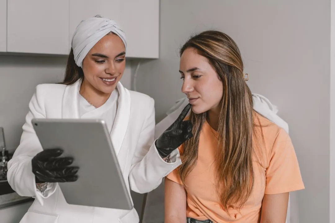 Botox specialist consulting a female patient with digital tablet, discussing treatment expectations and visible results over time. 