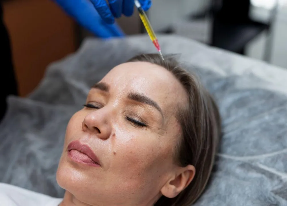 Aesthetic specialist performing PRP injection on a woman’s forehead to rejuvenate skin, reduce fine lines, and stimulate collagen production for youthful results.