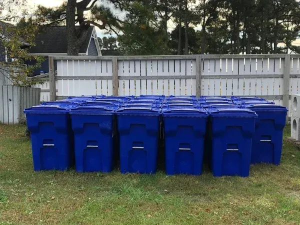 Blue recycling bins lined up in a residential neighborhood ready for garbage bin cleaning
