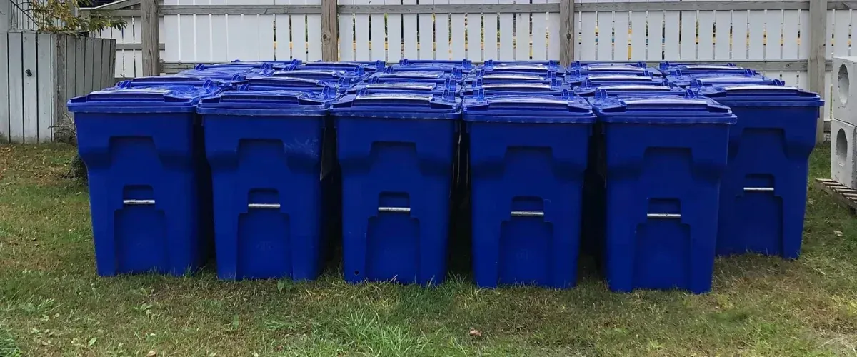 Blue recycling bins lined up in a residential neighborhood ready for garbage bin cleaning