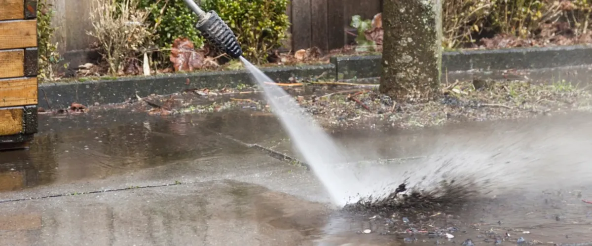 Close-up of pressure washer removing grime from stone patio pavers
