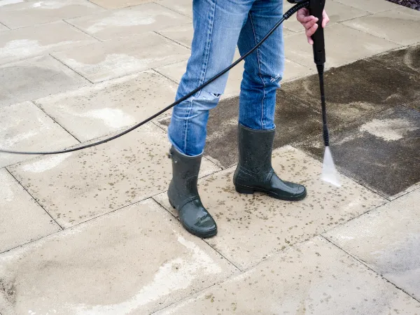 Close-up of pressure washer removing grime from stone patio pavers