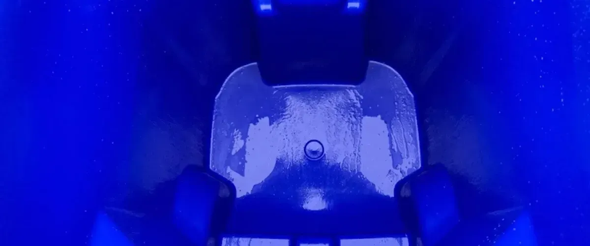 Brightly lit, freshly cleaned interior of a blue trash bin.