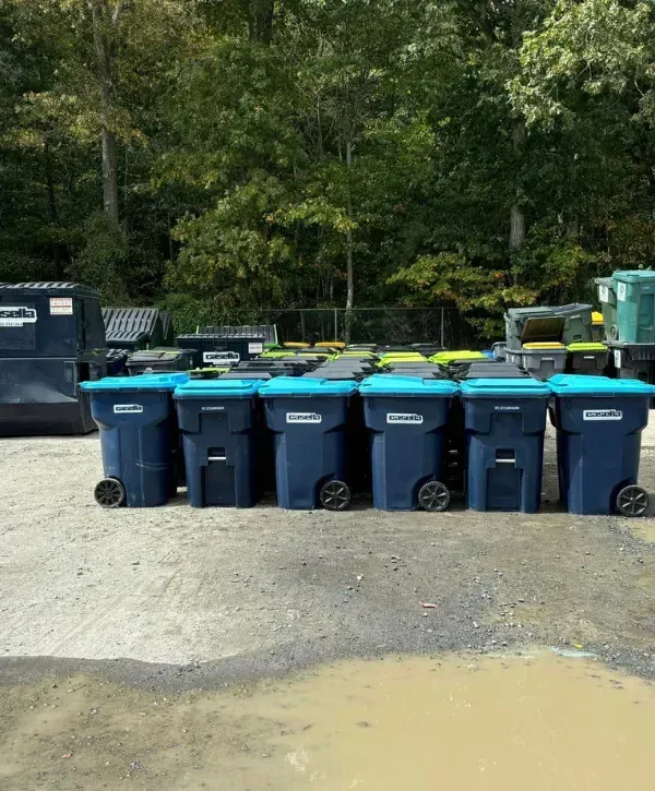 Group of blue trash bins with green lids arranged at a waste collection yard.