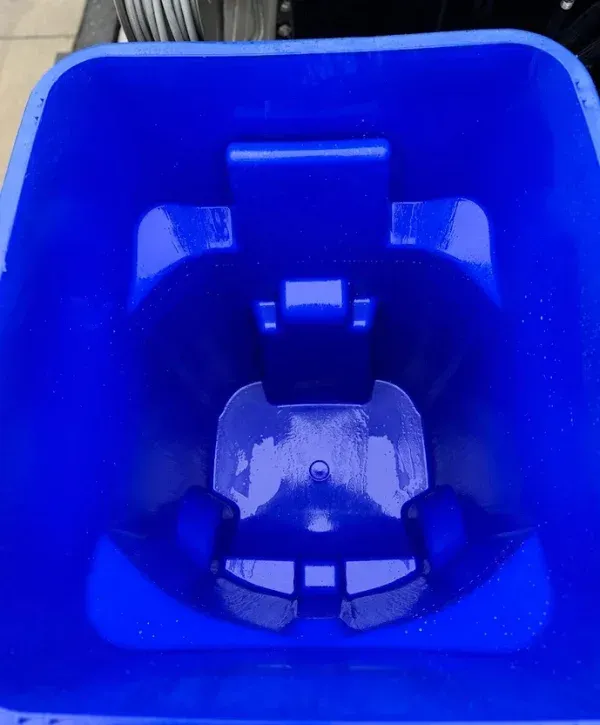 A close-up, high-angle view looking down into a clean, empty, vibrant blue recycling bin.